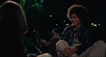 Movie still from “Pixote” (1980), directed by Hector Babenco – A woman sitting next to a man on a laptop; Medium shot, Over the shoulder angle