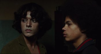 Movie still from “Pixote” (1980), directed by Hector Babenco – Two young men standing next to each other in a dark room; Close Up shot, Low angle