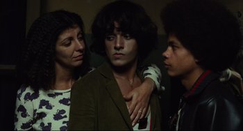 Movie still from “Pixote” (1980), directed by Hector Babenco – Three people are posing for a picture in a room; Medium shot, Low angle