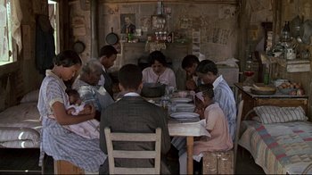 Movie still from “Places in the Heart” (1984), directed by Robert Benton – A group of people sitting at a table with plates; Wide shot, High angle