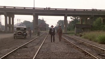 Movie still from “Places in the Heart” (1984), directed by Robert Benton – Two men are standing on train tracks in front of a bridge; Wide shot, High angle