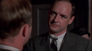 Movie still from “Places in the Heart” (1984), directed by Robert Benton – A man wearing a suit and tie talking to another man in front of a mirror; Close Up shot, Over the shoulder angle