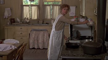 Movie still from “Places in the Heart” (1984), directed by Robert Benton – A woman standing in a kitchen preparing a meal; Medium shot, Over the shoulder angle