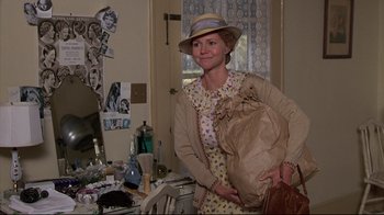 Movie still from “Places in the Heart” (1984), directed by Robert Benton – A woman holding a brown paper bag in a room; Medium shot, Over the shoulder angle