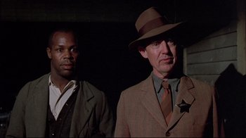 Movie still from “Places in the Heart” (1984), directed by Robert Benton – A man in a suit and a man in a hat; Medium shot, Low angle