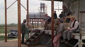 Movie still from “Places in the Heart” (1984), directed by Robert Benton – A group of people standing around a building; Wide shot, High angle