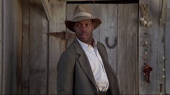 Movie still from “Places in the Heart” (1984), directed by Robert Benton – A man wearing a suit and hat standing in front of a barn door; Close Up shot, Low angle