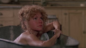Movie still from “Places in the Heart” (1984), directed by Robert Benton – A woman sitting on a couch with her arms crossed; Close Up shot, Over the shoulder angle