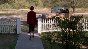 Movie still from “Places in the Heart” (1984), directed by Robert Benton – A woman walking down a sidewalk near a car; Wide shot, Low angle