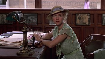 Movie still from “Places in the Heart” (1984), directed by Robert Benton – A woman sitting at a desk with a hat on; Medium shot, Low angle
