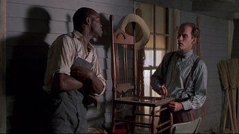 Movie still from “Places in the Heart” (1984), directed by Robert Benton – Two men sitting in front of a chair in a room; Medium shot, Low angle