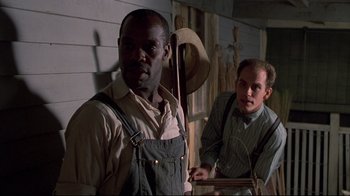 Movie still from “Places in the Heart” (1984), directed by Robert Benton – Two men standing next to each other in front of a building; Medium shot, Low angle