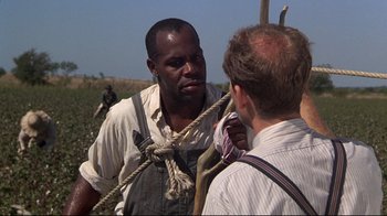 Movie still from “Places in the Heart” (1984), directed by Robert Benton – A man in overalls is talking to another man; Medium shot, Over the shoulder angle