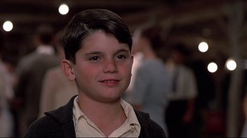 Movie still from “Places in the Heart” (1984), directed by Robert Benton – A young boy is smiling for the camera; Close Up shot, Over the shoulder angle