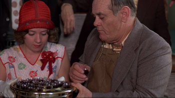 Movie still from “Places in the Heart” (1984), directed by Robert Benton – An older man and a young girl are looking at a cake; Close Up shot, High angle