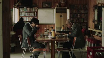 Two men sitting at a table in front of two phones