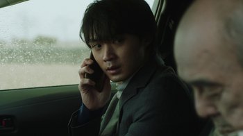 A man in a suit talking on a cell phone in a car
