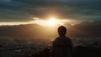 A person standing on top of a hill looking at a sunset