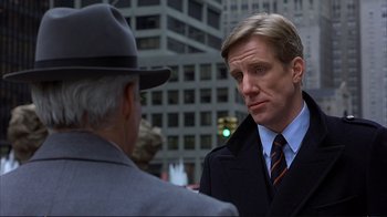 Movie still from “Planes, Trains & Automobiles” (1987), directed by John Hughes – A man wearing a suit and a hat talking to another man wearing a suit and a hat; Close Up shot, Over the shoulder angle