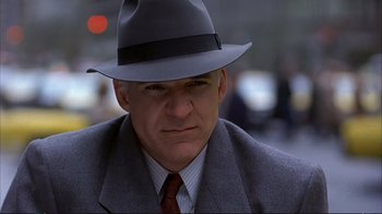 Movie still from “Planes, Trains & Automobiles” (1987), directed by John Hughes – A person wearing a suit and a hat; Close Up shot, Low angle