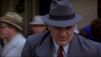 Movie still from “Planes, Trains & Automobiles” (1987), directed by John Hughes – A person wearing a suit and a hat; Close Up shot, Low angle