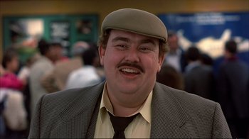 Movie still from “Planes, Trains & Automobiles” (1987), directed by John Hughes – A person wearing a hat and a suit; Close Up shot, Over the shoulder angle