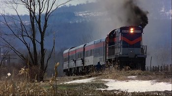 Movie still from “Planes, Trains & Automobiles” (1987), directed by John Hughes – A train traveling down train tracks next to a forest; Extreme Wide shot, High angle