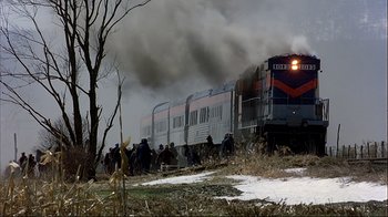 Movie still from “Planes, Trains & Automobiles” (1987), directed by John Hughes – A train traveling down train tracks next to a forest; Extreme Wide shot, High angle
