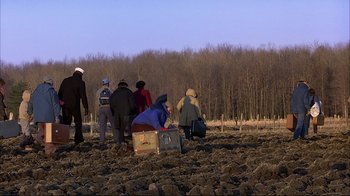 Movie still from “Planes, Trains & Automobiles” (1987), directed by John Hughes – A group of people standing in a field with luggage; Extreme Wide shot, High angle
