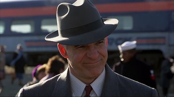Movie still from “Planes, Trains & Automobiles” (1987), directed by John Hughes – A person wearing a suit and a hat; Close Up shot, Low angle