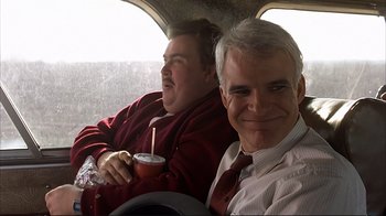 Movie still from “Planes, Trains & Automobiles” (1987), directed by John Hughes – Two men sitting next to each other in a vehicle; Medium shot, Over the shoulder angle