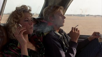 Movie still from “Planes, Trains & Automobiles” (1987), directed by John Hughes – A man and a woman smoke cigarettes while sitting in a car; Medium shot, Over the shoulder angle