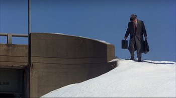 Movie still from “Planes, Trains & Automobiles” (1987), directed by John Hughes – A man in a suit is walking up a ramp; Extreme Wide shot, Low angle
