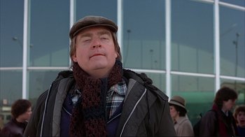 Movie still from “Planes, Trains & Automobiles” (1987), directed by John Hughes – A man wearing a hat and a scarf outside; Close Up shot, Low angle