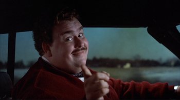 Movie still from “Planes, Trains & Automobiles” (1987), directed by John Hughes – A man in a red jacket sitting in the drivers seat of a car; Close Up shot, Low angle