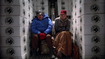 Movie still from “Planes, Trains & Automobiles” (1987), directed by John Hughes – A couple of people sitting on top of a subway train; Wide shot, Overhead angle