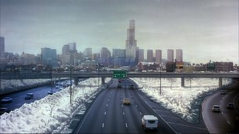 Movie still from “Planes, Trains & Automobiles” (1987), directed by John Hughes – Cars driving on a highway with snow on the ground; Extreme Wide shot, High angle