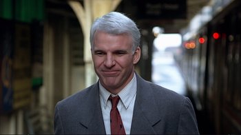 Movie still from “Planes, Trains & Automobiles” (1987), directed by John Hughes – A person wearing a suit and tie; Close Up shot, Over the shoulder angle
