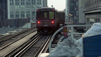Movie still from “Planes, Trains & Automobiles” (1987), directed by John Hughes – A train on the tracks in a city; Extreme Wide shot, High angle