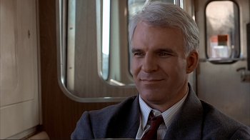 Movie still from “Planes, Trains & Automobiles” (1987), directed by John Hughes – A person wearing a suit and tie; Close Up shot, Over the shoulder angle