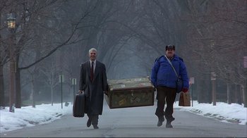 Movie still from “Planes, Trains & Automobiles” (1987), directed by John Hughes – Two men walking down the street carrying a trunk; Wide shot, Low angle