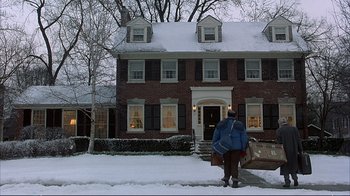 Movie still from “Planes, Trains & Automobiles” (1987), directed by John Hughes – A person walking down the street in front of a brick house; Extreme Wide shot, Low angle