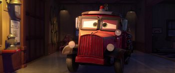 Movie still from “Planes: Fire & Rescue” (2014), directed by Bobs Gannaway – A red fire truck with a fireman's helmet on it's head; Wide shot, Low angle