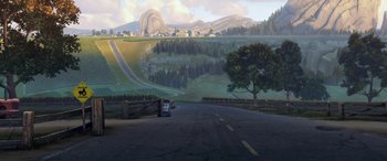 Movie still from “Planes: Fire & Rescue” (2014), directed by Bobs Gannaway – A truck driving down a road near a forest; Extreme Wide shot, High angle
