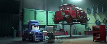 Movie still from “Planes: Fire & Rescue” (2014), directed by Bobs Gannaway – A car is parked in a garage next to a truck; Wide shot, Low angle