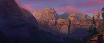 Movie still from “Planes: Fire & Rescue” (2014), directed by Bobs Gannaway – An airplane is flying over a mountain range at sunset; Extreme Wide shot, Overhead angle