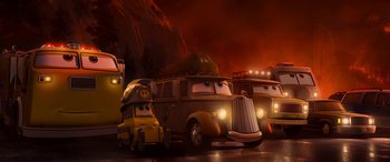 Movie still from “Planes: Fire & Rescue” (2014), directed by Bobs Gannaway – A group of cartoon cars parked on top of a road; Wide shot, Low angle
