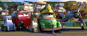 Movie still from “Planes: Fire & Rescue” (2014), directed by Bobs Gannaway – A green truck is parked next to many other vehicles; Wide shot, Low angle