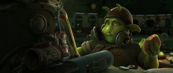 Movie still from “Planet 51” (2009), directed by Javier Abad – A character from shrek sitting in front of a table; Medium shot, High angle