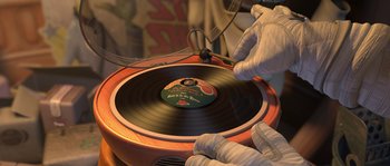 Movie still from “Planet 51” (2009), directed by Javier Abad – A person in white gloves is playing a record on a record player; Extreme Close Up shot, High angle